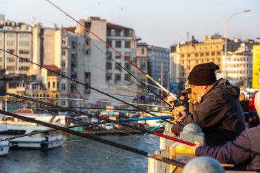 İSTANBUL, TURKEY - 10 Nisan 2022: Güneşli bir günde Türkiye 'nin İstanbul kentindeki Galata köprüsünde balıkçılar