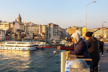 İSTANBUL, TURKEY - 10 Nisan 2022: Güneşli bir günde Türkiye 'nin İstanbul kentindeki Galata köprüsünde balıkçılar