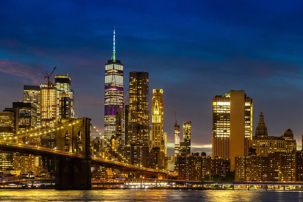 ブルックリン橋とニューヨークの日没後のマンハッタンのダウンタウンのパノラマの夜景 — ストック写真