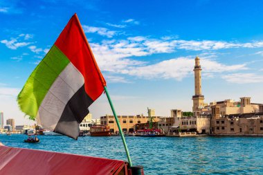 Abra 'ya karşı Birleşik Arap Emirlikleri bayrağına odaklan. Eski ahşap tekne ve Dubai Körfezi' ndeki Dubai Mescidi Camii.