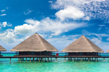 Su Villaları (Bungalovlar) ve yaz günü Maldivler 'deki tropik sahildeki ahşap köprü