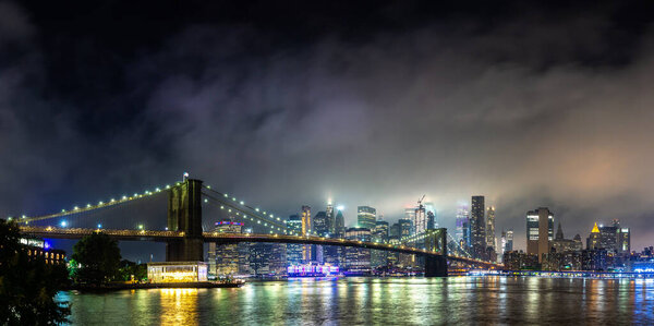 Panorama of Brooklyn Bridge and panoramic night view of downtown Manhattan after sunset in New York City, USA