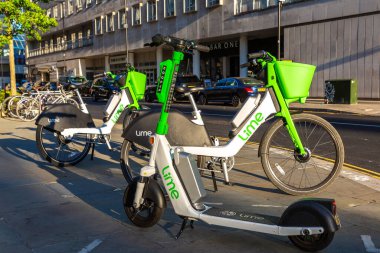 LONDON, İngiltere - 17 Haziran 2022: Güneşli bir yaz gününde Londra 'da bir sokakta modern Lime elektrikli bisiklet ve elektrikli scooter