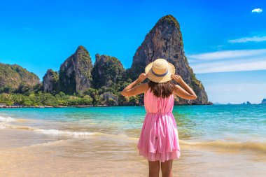 Tropikal Railay Sahili, Yengeç, Tayland 'da pembe elbise ve hasır şapka giyen güzel bir kadın.