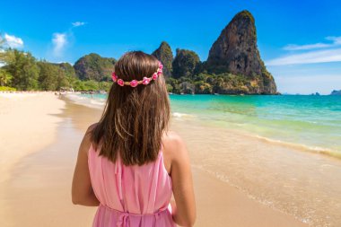 Genç ve güzel bir kadın pembe elbise giyiyor ve tropikal Railay Sahili 'nde çiçek çelengi, Krabi, Tayland