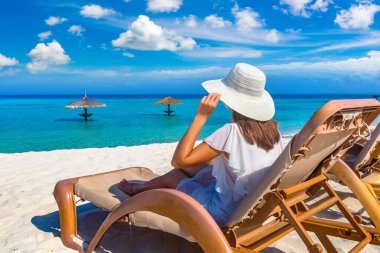 Güneşli bir yaz gününde lüks bir tropik plajda güneşlenen güzel bir kadın.