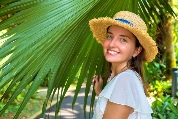 年轻美丽的女子正靠在热带棕榈树的大叶上摆姿势 — 图库照片