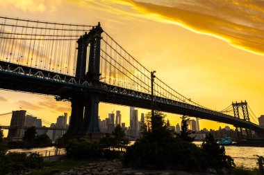 Brooklyn Köprüsü 'nün günbatımı ve New York City, ABD' deki Manhattan şehir merkezinin panoramik manzarası.