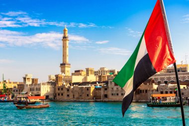 Abra 'ya karşı Birleşik Arap Emirlikleri bayrağına odaklan. Eski ahşap tekne ve Dubai Körfezi' ndeki Dubai Mescidi Camii.