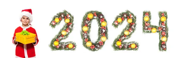 ボーイサンタクロースはクリスマスプレゼントと白い背景に隔離されたクリスマスツリーの枝で作られた2024の番号を保持しています — ストック写真