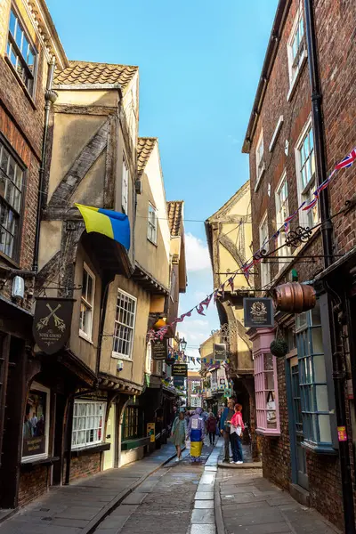 YORK, İngiltere - 10 Haziran 2022: The Shambles - New York 'taki Old Town' da güneşli bir yaz günü Kuzey Yorkshire, İngiltere 'de bir ortaçağ caddesi
