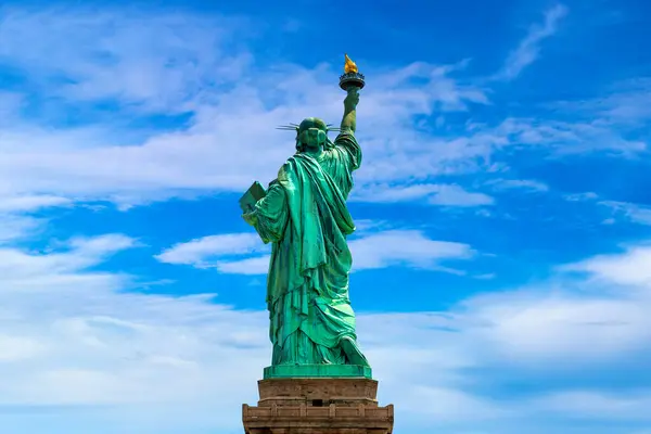Back of Statue of Liberty against blue sky with beautiful cloud background in New York City, NY, USA