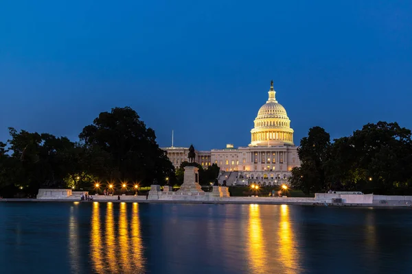 The United States Capitol building and Capitol Reflecting Pool at sunset at night in Washington DC, USA