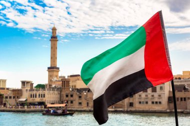 Abra 'ya karşı Birleşik Arap Emirlikleri bayrağına odaklan. Eski ahşap tekne ve Dubai Körfezi' ndeki Dubai Mescidi Camii.