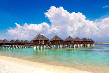 Su Villaları (Bungalovlar) ve yaz günü Maldivler 'deki tropik sahildeki ahşap köprü