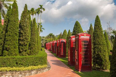 Güneşli bir günde Nong Nooch Tropik Botanik Bahçesi, Pattaya, Tayland 'da dekoratif İngiliz telefon kulübeleri