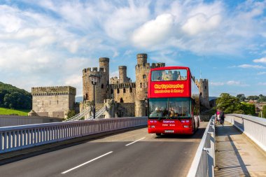 KONWY, İngiltere - 17 AĞUSTOS 2023: Çift katlı gezi otobüsü ve güzel bir yaz gününde Galler 'deki Conwy Castle, Birleşik Krallık