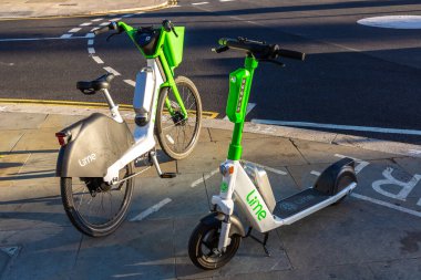 LONDON, UK - JUNE 17, 2022: Modern Lime electric bike and electric scooter on a street in London in a sunny summer day, UK clipart