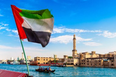 Abra 'ya karşı Birleşik Arap Emirlikleri bayrağına odaklan. Eski ahşap tekne ve Dubai Körfezi' ndeki Dubai Mescidi Camii.