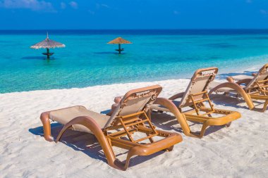 Güneşli bir yaz gününde tropik cennet okyanus plajında güneş yatağı ve şemsiye.