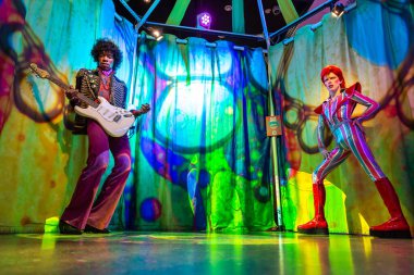 LONDON, UK - JANUARY 28, 2025: Iconic wax figures of Jimi Hendrix and David Bowie in a vibrant, psychedelic setup at Madame Tussauds London, showcasing two legendary music icons clipart