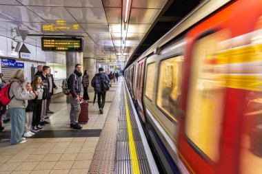 LONDON, İngiltere - 29 Ocak 2025: Bir Londra metro treni hareket bulanıklığıyla Embankment İstasyonu 'na varır ve şehir taşımacılığının hızını yakalar. Yolcular biniş için platformda bekliyor.