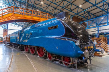 YORK, İngiltere - 6 Şubat 2025: Iconic Mallard buharlı lokomotifi (Hayır. 4468), dünya hız rekoru sahibi, canlı mavi dizayn ve çarpıcı kırmızı tekerleklerle York 'taki Demiryolu Müzesi' nde sergilenmektedir.