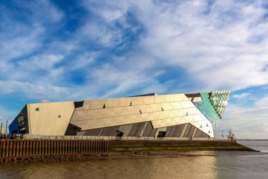 HULL, UK - 22 Şubat 2025: Kingston 'daki Derin Akvaryum Hull, İngiltere' de, Humber Estuary 'nin üzerinde gün batımında parlar. Bu deniz eğlencesi köpekbalıkları da dahil olmak üzere 5000 'den fazla deniz canlısına ev sahipliği yapıyor.