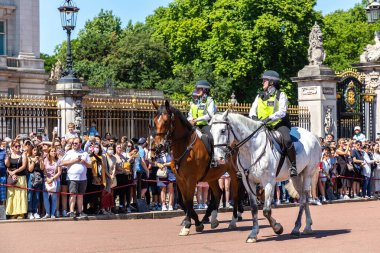 LONDON, İngiltere - 17 Haziran 2022: Londra 'da güneşli bir yaz günü Buckingham Sarayı' nın önünde düzenlenen koruma seremonisinin değişmesi için Metropolitan atlı polis devriyesi