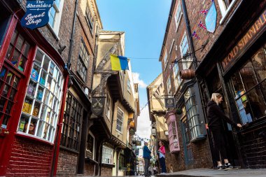YORK, İngiltere - 10 Haziran 2022: The Shambles - New York 'taki Old Town' da güneşli bir yaz günü Kuzey Yorkshire, İngiltere 'de bir ortaçağ caddesi