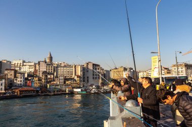 İSTANBUL, TURKEY - 10 Nisan 2022: Güneşli bir günde Türkiye 'nin İstanbul kentindeki Galata köprüsünde balıkçılar