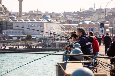İSTANBUL, TURKEY - 10 Nisan 2022: Güneşli bir günde Türkiye 'nin İstanbul kentindeki Galata köprüsünde balıkçılar