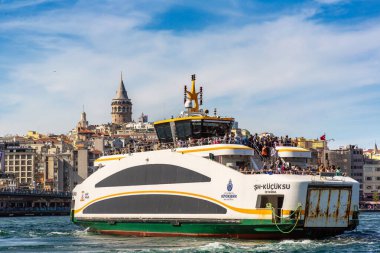 İSTANBUL, TURKEY - 10 Nisan 2022: Güneşli bir günde Türkiye 'nin İstanbul kentindeki Golden Horn ve Galata kulesinin körfezinde yolcu feribotu