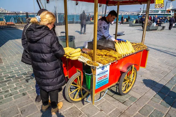 İSTANBUL, TURKEY - 10 Nisan 2022: Türkiye 'nin İstanbul kentinde, güneşli bir günde geleneksel Türk ızgara mısır ve kestane satıcısı