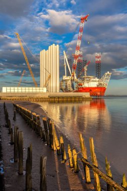 HULL, UK - 17 Nisan 2025: Rüzgar Tepesi, modern bir açık deniz rüzgar yükleme gemisi, Siemens Gamesa rüzgar türbini bileşenlerini off-shore rüzgar çiftliklerine yerleştirmek üzere İngiltere 'nin Hull kentinde demirledi.