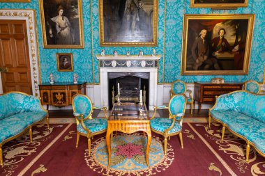 YORKSHIRE, İngiltere - 30 Haziran 2025: Mavi ipek duvar kaplamalı, avizeli ve portre resimli zarif Reynolds Odası Kuzey Yorkshire, İngiltere 'de Howard Kalesi' nde