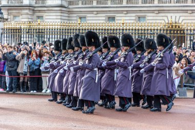 Londra, Buckingham Sarayı 'ndaki muhafız değişiminde, izleyiciler tarafından izlenen merasim üniformalı bir İngiliz muhafız alayı tüfeklerle yürür.