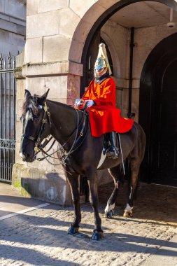 LONDON, İngiltere - 30 HAZİRAN 2025: Kırmızı üniformalı ve altın kaplama miğferli bir Süvari askeri, İngiliz askeri ve kraliyet geleneklerinin kilit bir direği olan Horse Guards, Londra 'da at sırtında nöbet tutuyor