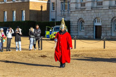 LONDON, İngiltere - 30 Ocak 2025: Kırmızı tören üniforması ve altın kasklı bir süvari subayı, kraliyet geleneği olan At Muhafızları Geçit Töreni sırasında elinde kılıçla yürür.