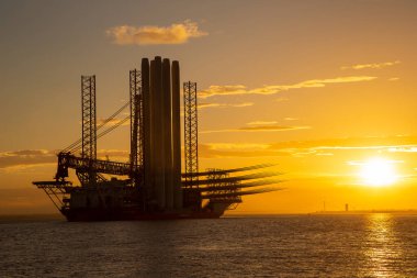 HULL, İngiltere - OCTOBER 06, 2025: Offshore kurulum gemisi Wind Peak Hull, İngiltere 'den ayrılarak, gün batımında açıklardaki rüzgar çiftlikleri için Siemens Gamesa rüzgar türbini bileşenleri taşıyor