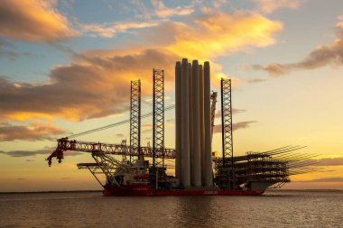 HULL, İngiltere - OCTOBER 06, 2025: Offshore kurulum gemisi Wind Peak Hull, İngiltere 'den ayrılarak, gün batımında açıklardaki rüzgar çiftlikleri için Siemens Gamesa rüzgar türbini bileşenleri taşıyor