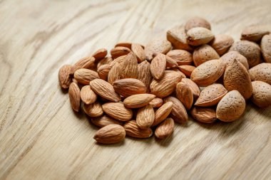 Ahşap zemin üzerinde kabuklu çiğ badem ve badem soyulmuş. Fındık, beslenme ve çiğ gıda konsepti