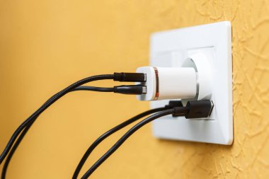 USB portlarında beyaz elektrik prizi ve çoklu siyah beyaz kablolu USB şarj aleti. Güç arzı ve şarj etme kavramı