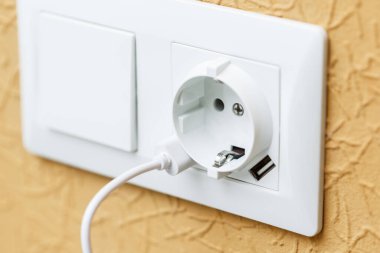 USB limanlarının beyaz kablosuna takılmış beyaz elektrik prizi. Güç arzı ve şarj etme kavramı
