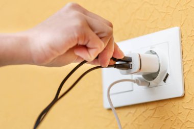 USB portlarında bulunan beyaz elektrik prizine takılı siyah kabloyu USB şarj cihazına takar. Güç arzı ve şarj etme kavramı