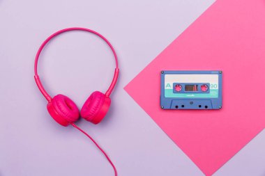 Pembe ve pembe kulaklıklı eflatun arkaplanlı mavi ses kaseti. Analog ses müzik kavramı