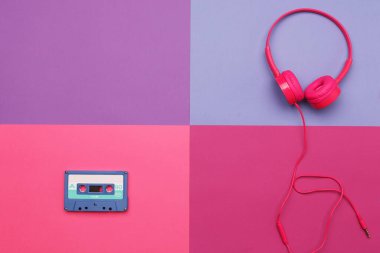 Renkli kağıt arka planda mavi ses kaseti ve pembe kulaklıklar. Analog ses müzik kavramı
