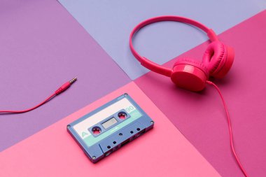 Renkli kağıt arka planda mavi ses kaseti ve pembe kulaklıklar. Analog ses müzik kavramı