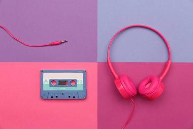 Renkli kağıt arka planda mavi ses kaseti ve pembe kulaklıklar. Analog ses müzik kavramı