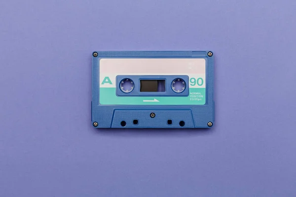 Blue audio cassette on a lilac background. Analog audio music concept